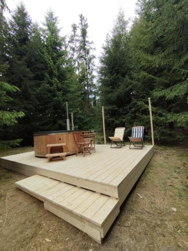 a wooden deck with two chairs and a table at domek w zaczarowanym lesie in Istebna
