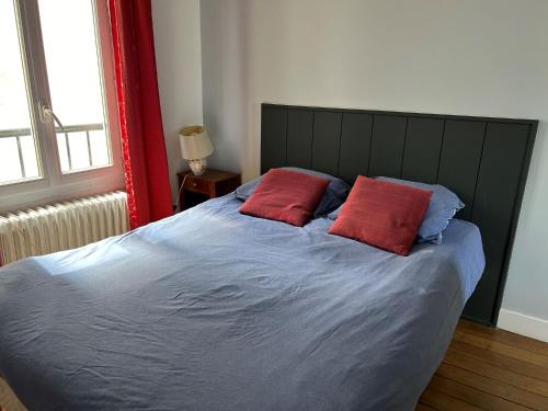 - un lit avec 2 oreillers rouges dans l'établissement L'appartement Jean Moulin, à Paris