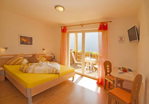 a bedroom with a yellow bed and a balcony at Gasthaus Jaufenblick in San Martino