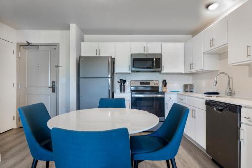 a kitchen with a white table and blue chairs at Soka Suites Dallas - Las Colinas in Irving