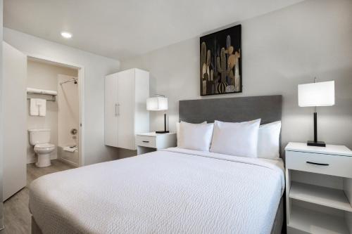 a bedroom with a large white bed and a bathroom at Soka Suites Dallas - Las Colinas in Irving