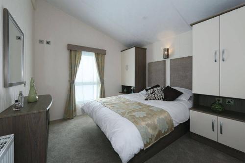 a bedroom with a large bed and a window at Castaways Holiday Park in Bacton