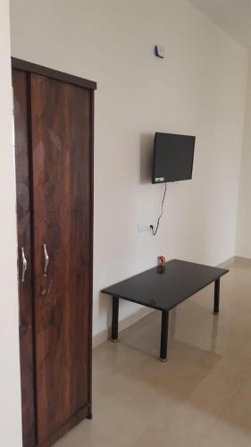 a black table in front of a wall with a tv at Fourseason frankcottage in Chikmagalūr