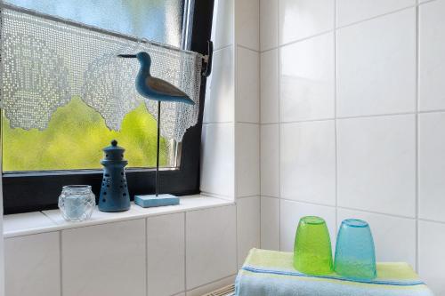 a bird figurine sitting on a window sill in a bathroom at An der Silberfuchsbörse in Engbüttel