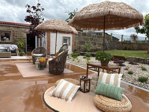 a patio with two umbrellas and chairs and a table at Tibo - Casal do Conde in Caldas de Reis