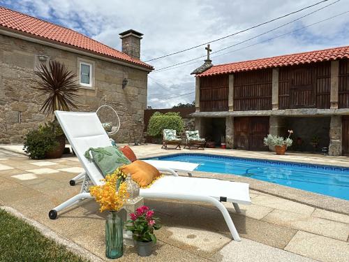 a white chair sitting next to a swimming pool at Tibo - Casal do Conde in Caldas de Reis