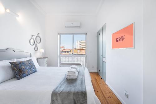 a white bedroom with a large bed and a window at GuestReady - Gold Leaf in Porto