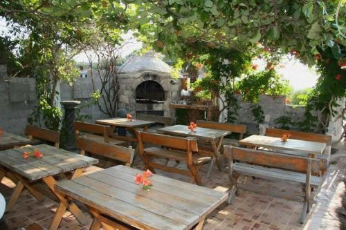 un patio extérieur avec des tables et des bancs en bois et un four dans l'établissement Violit Apartments&Restaurant, à Sutomore
