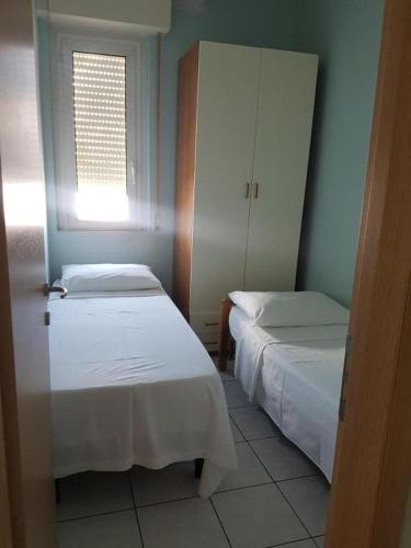 Habitación pequeña con 2 camas y ventana en Hotel Acapulco, en Rímini