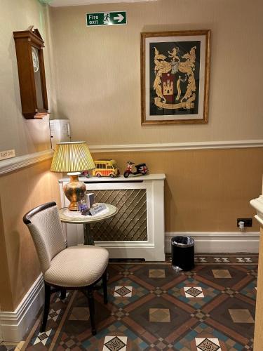 a room with a table and a chair and a lamp at Chester House Guest House in Chester