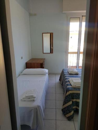 Habitación con 2 camas y espejo. en Hotel Acapulco, en Rímini