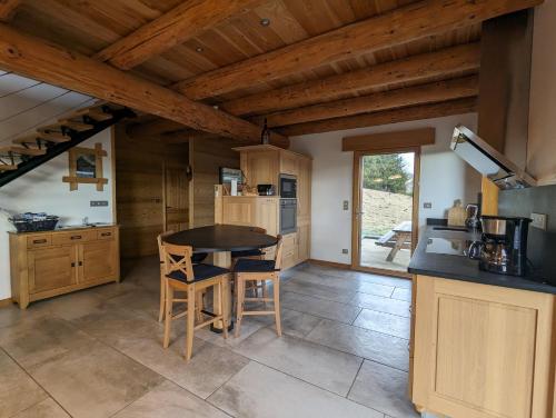 Il comprend une cuisine avec des plafonds en bois, une table et des chaises. dans l'établissement GÎTE EN FAMILLE EN PLEINE NATURE -Regard sur le Mézenc, à Chaudeyrolles