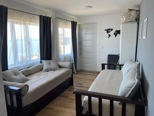 Una sala de estar con un sofá y dos ventanas. en Los Dones Departamentos DAT, en San Carlos de Bariloche