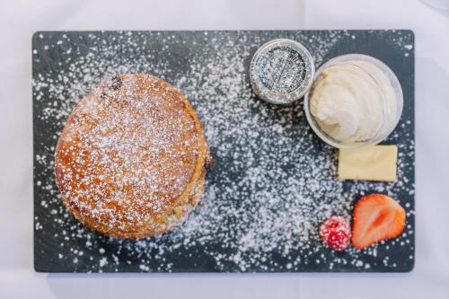 a pastry with powdered sugar and a bowl of butter and strawberries at Muthu Newton Hotel (Near Inverness Airport) in Nairn