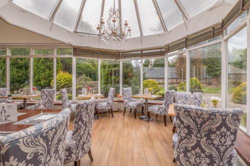 a conservatory with tables and chairs and a chandelier at Muthu Newton Hotel (Near Inverness Airport) in Nairn