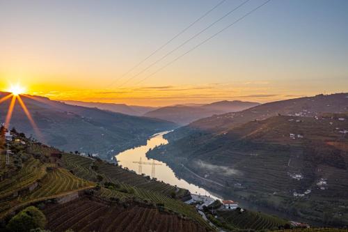a view of a river with the sun setting in the background at Casa Vale do Douro in Mesão Frio