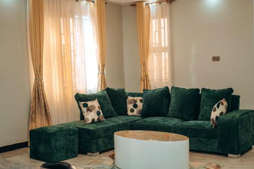 a living room with a green couch with pillows at Peacefull home Too in Kampala