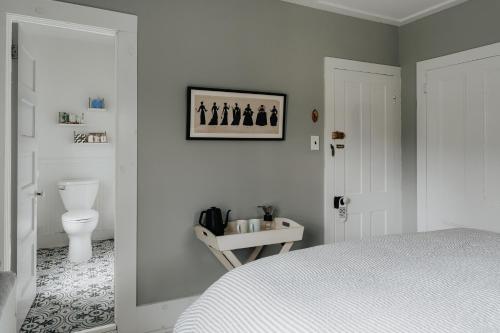 a white bedroom with a bed and a toilet at The Yarra in Roscoe