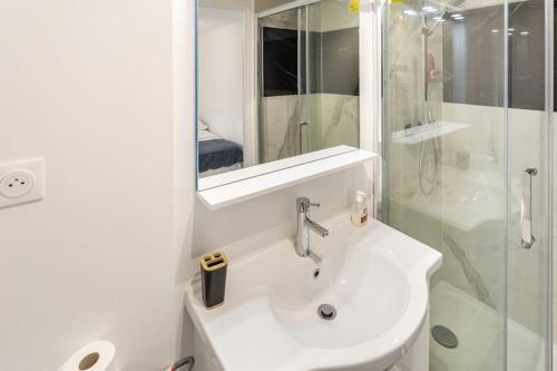 La salle de bains blanche est pourvue d'un lavabo et d'une douche. dans l'établissement Studio cosy proche Paris Orly, à Morangis