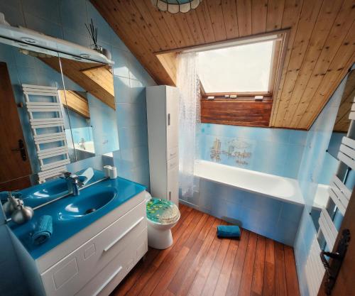 uma casa de banho azul com um lavatório, uma banheira e uma janela. em VILLA "Le Jardin" - Piscine chauffée couloir 12m - Spa Balnéo Hammam - 4 Chambres dont une Love Room de 35m2 avec lit rond, vidéo projecteur Netflix, climatisation em Jardin