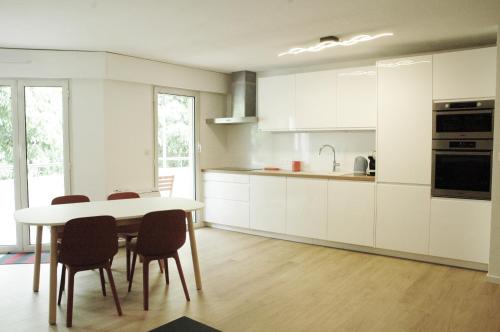 une cuisine avec des armoires blanches et une table et des chaises dans l'établissement Vaste et lumineux appartement, à Antibes