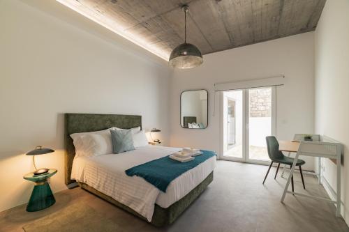ein Schlafzimmer mit einem Bett mit einem Schreibtisch und einem Stuhl in der Unterkunft Xª Deluxe Apartments in Ribeira Grande