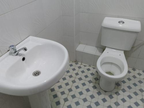 y baño con aseo blanco y lavamanos. en MUSEUM VIEW HOTEL KISUMU CITY-MILIMANI en Kisumu
