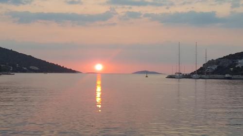 a sunset over a body of water with boats at Apartment TRI MASLINE with seaview in Trogir
