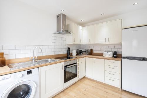 a kitchen with white cabinets and a sink and a dishwasher at Host & Stay - Milbanke House in Seaham