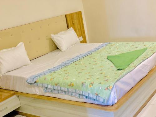 Una cama con una manta verde encima. en THE SILVER TULIP en Ludhiana