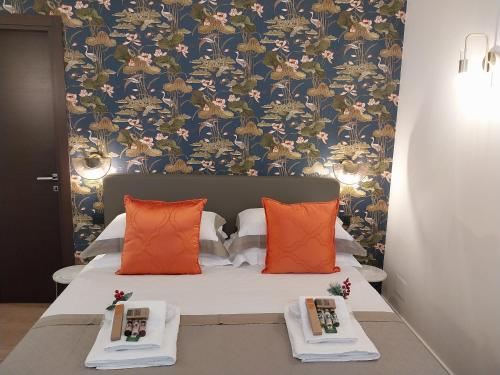 a bedroom with a bed with orange pillows and a wallpaper at Napoli Mariana Luxury in Naples