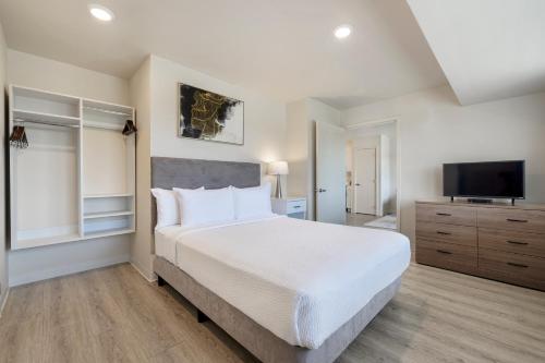 アービングにあるSoka Suites Dallas - Las Colinasのベッドルーム(大型ベッド1台、薄型テレビ付)