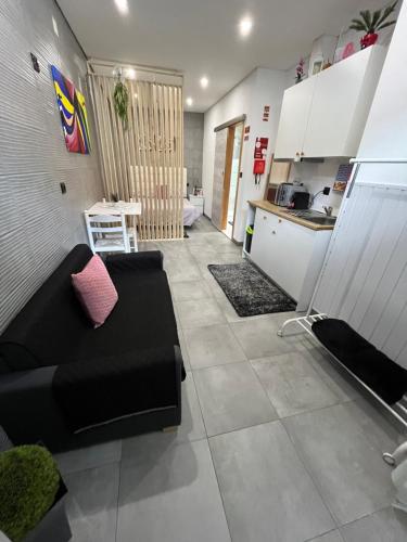Una sala de estar con un sofá negro y una cocina. en Alojamento Joaninha Douro 1, en Peso da Régua