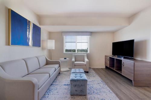 a living room with a couch and a flat screen tv at Soka Suites Dallas - Las Colinas in Irving