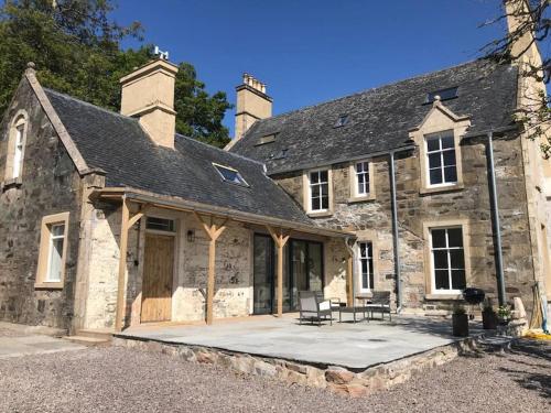 an old stone house with a patio in front of it at Stylish Scottish Manor, Coillemore House in Kyle of Lochalsh