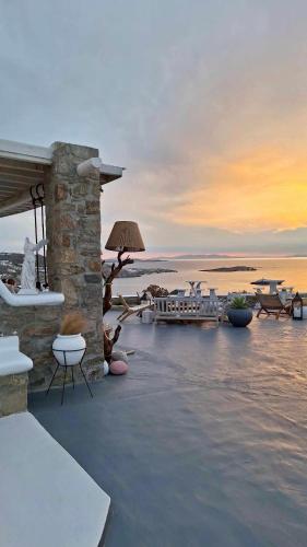 a sunset over the ocean with chairs and tables at Vougli View Mykonos in Drafaki