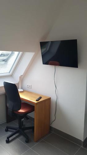 Elle comprend un bureau avec une chaise et une télévision murale. dans l'établissement Appartement T2 hippodrome, à Séné