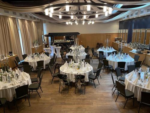 a room with white tables and chairs and a piano at Hotel Gräfrather Hof in Solingen