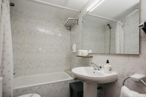 a white bathroom with a sink and a bath tub at La Trobada Hotel Sport in Ripoll