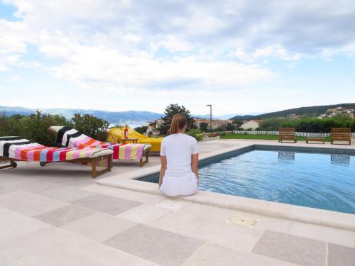 a woman sitting on the edge of a swimming pool at Mariosa 2 in Vrbnik