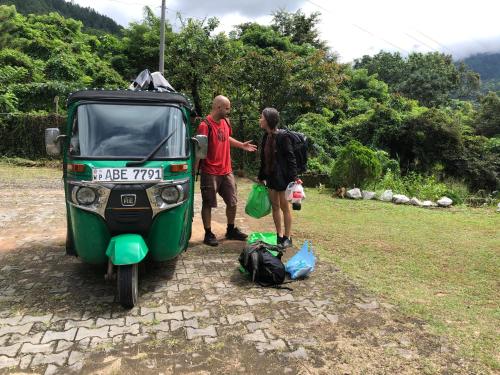 two men are standing next to a green vehicle at Hamadhi guest in Haldummulla