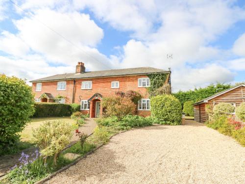 an exterior view of a brick house with a driveway at Horseshoe Cottage in Romsey