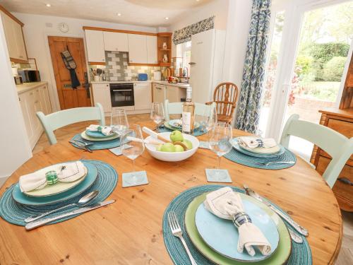 a wooden table with plates and bowls of fruit on it at Horseshoe Cottage in Romsey