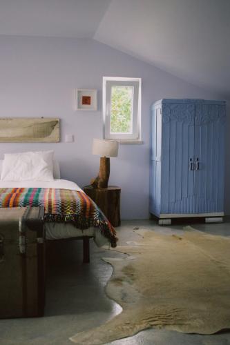 a bedroom with a bed and a blue cabinet at Casa Oliva - Casa da Mata in Porto de Mós