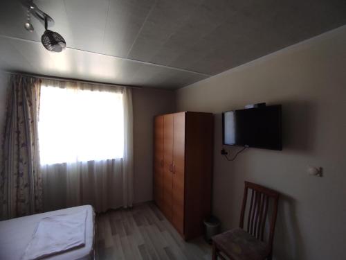 een slaapkamer met een bed en een televisie aan de muur bij Вила Никови in Durankulak