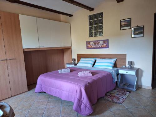 een slaapkamer met een groot bed met een paarse sprei bij B&B Bertaina Mauro in Cavallermaggiore