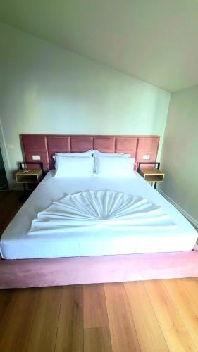 a large white bed in a bedroom with wooden floors at Hotel Noel in Vlorë