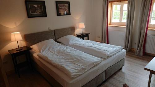 Lüdersburger Strasse 15d في Lüdersburg: غرفة نوم بسرير مع شراشف بيضاء ومصباحين