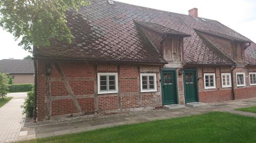 uma antiga casa de tijolos vermelhos com portas verdes em Lüdersburger Strasse 15d em Lüdersburg