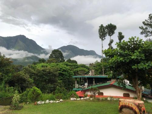 a house in a field with mountains in the background at Hamadhi guest in Haldummulla